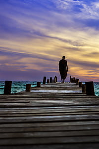 man walking on wooden dock at daytime thumbnail