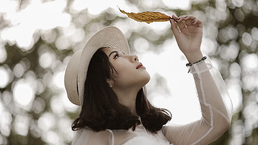 Woman Wearing White Long Sleeve Scoop-neck Top While Holding Brown Leaf thumbnail