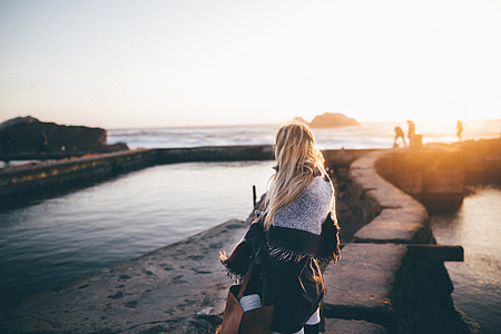 woman standing on concrete block near body of water during golden hour thumbnail