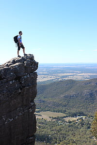 man standing on rock mountain cliff during daytime thumbnail