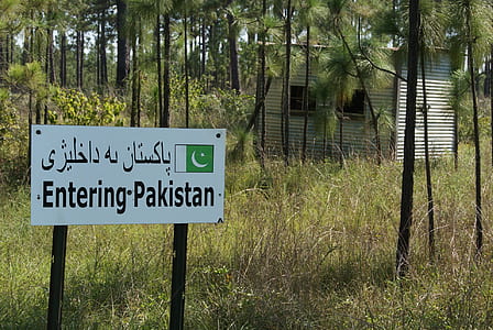 road signage displaying entering Pakistan text on road near shack thumbnail