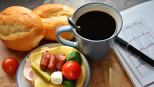 two baked breads beside ceramic cup filled with black liquid, bread knife and salad thumbnail