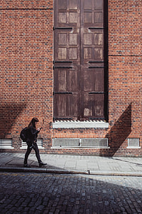 woman walking alongside the road beside building thumbnail
