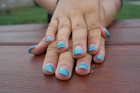 woman placing her hands with blue manicure on table thumbnail