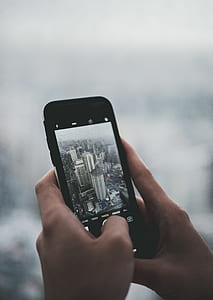 person taking photo of white high-rise building using smartphone thumbnail