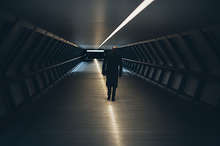 man in black coat standing at hallway between metal wall thumbnail