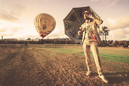 man holding umbrella while standing near hot air balloon thumbnail