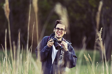 man holding DSLR camera standing in field thumbnail