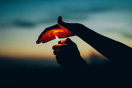 person holding lighted lighter during nighttime thumbnail