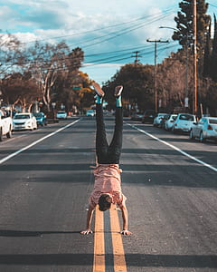 man doing hand stand at the center of the road thumbnail