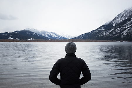man standing front of calm water and ice-capped mountain at daytime thumbnail