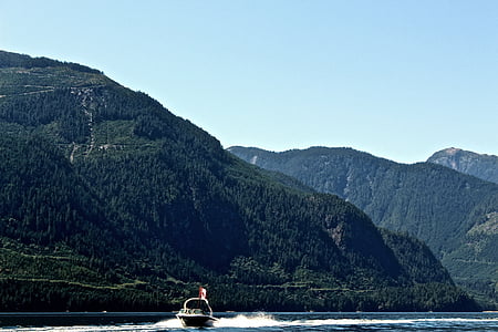 powerboat on body of water near mountain thumbnail