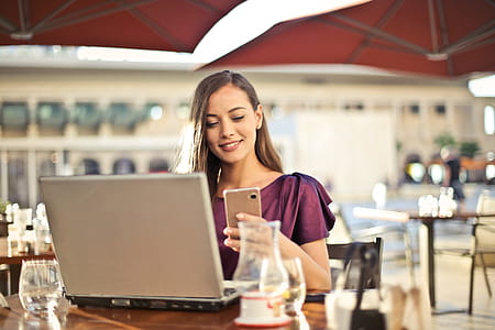 A young blonde woman wearing a purple red dress looking at her mobile phone screen at a restaurant thumbnail
