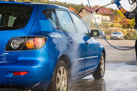 person cleaning blue 5-door hatchback using pressure washer thumbnail