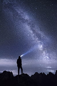 silhouette of man standing on rock under Milky Way Galaxy thumbnail