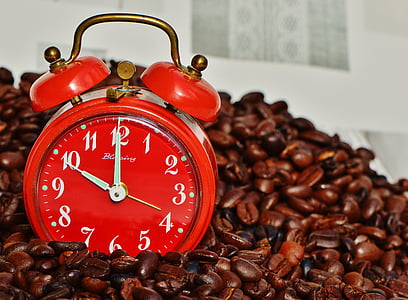 red double-bell alarm clock on top of coffee beans thumbnail