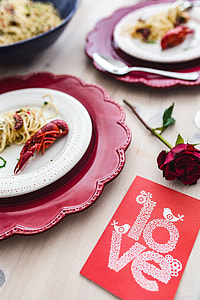 Fancy dinner with seafood pasta, crayfish and red wine by the table decorated with roses thumbnail