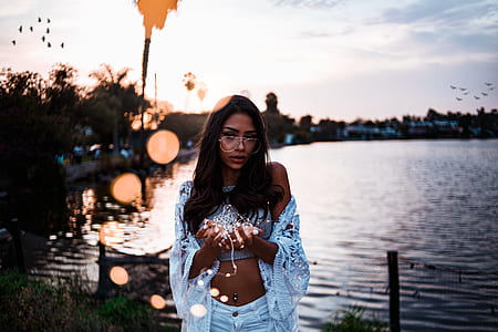 woman standing near lake holding string lights thumbnail
