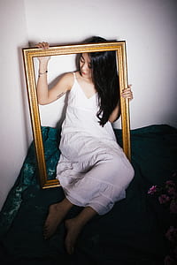 woman sitting on green surface holding brown photo frame thumbnail