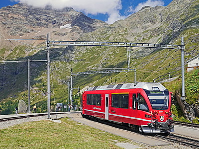 red and gray train in rail near mountain thumbnail
