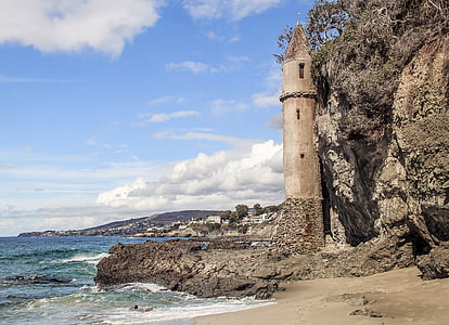 brown concrete lighthouse near body of water under blue and white sky thumbnail