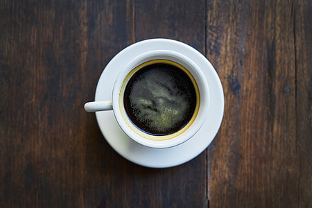 top view photo of white ceramic cup and saucer on brown wooden surface thumbnail