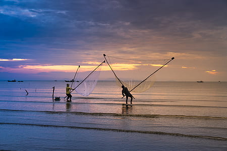 people standing seashore while holding fishnet thumbnail