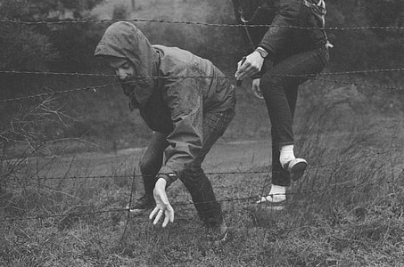 two person crossing barb wired fence thumbnail