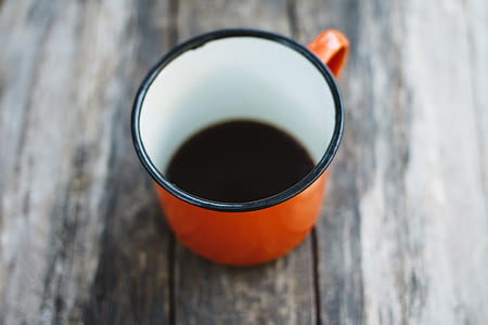 white and red ceramic cup on brown wooden panel thumbnail