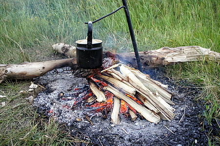 cooking pot on metal rod near wood log thumbnail