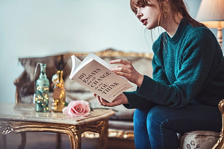 woman sitting on sofa chair reading book beside coffee table thumbnail