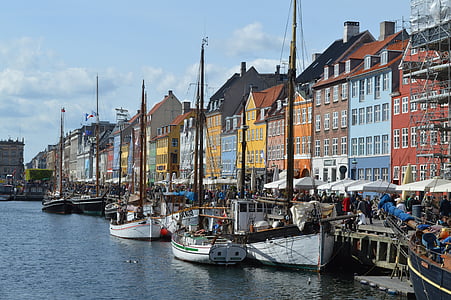 boats on body of water beside multi-colored buildings thumbnail
