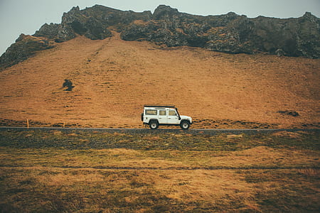 white car near brown cliff during daytime thumbnail