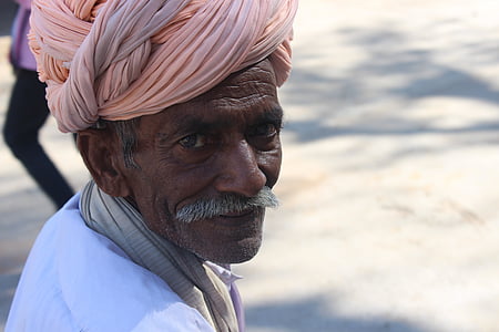 man wearing white top and pink headdress thumbnail