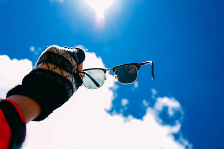 person holding sunglasses against the sunlight thumbnail