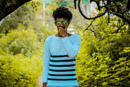 man in blue and black striped long-sleeved shirt standing near green leafed trees during daytime thumbnail