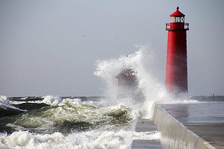 ocean water crashing on red lighthouse during daytime thumbnail