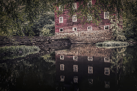 red wooden house surrounded by green leaf trees beside body of water thumbnail
