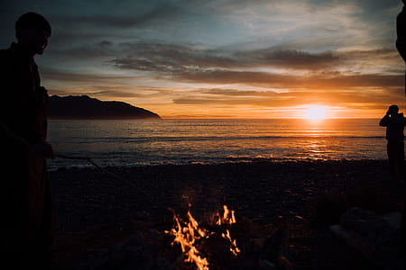 silhouette photography of man standing beside body of water thumbnail