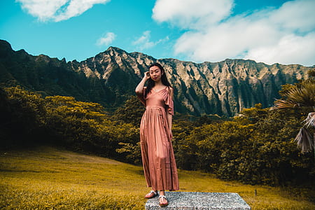 woman standing near green trees and fault block mountains during daytime thumbnail