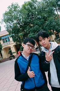 Man in Blue Hoodie Beside a Man in Black Jacket Standing Outdoors Under Blue and White Sunny Sky during Dayimte thumbnail