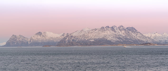 body of water near snow covered mountain during daytime thumbnail