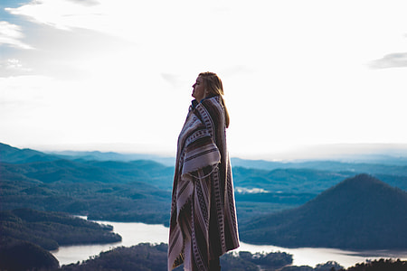 woman wearing white and brown coat standing on mountain thumbnail