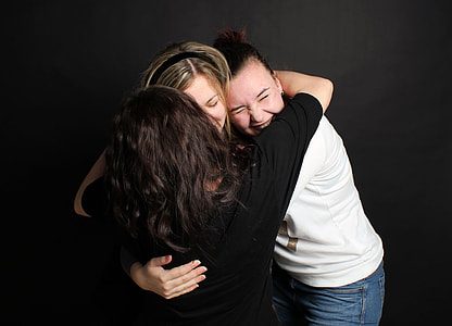 three women hugging each other photo thumbnail