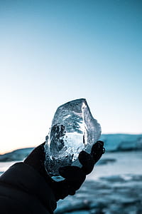 person holding ice block under blue sky during daytime thumbnail