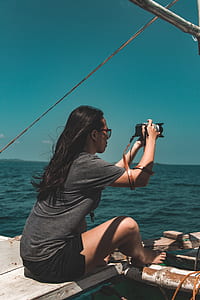 woman taking photo of sea using DSLR camera thumbnail