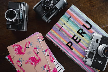 Old analog cameras and pink books on a wooden table thumbnail