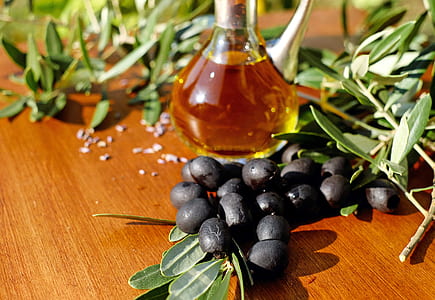 glass of oil above black fruits on brown wooden table thumbnail