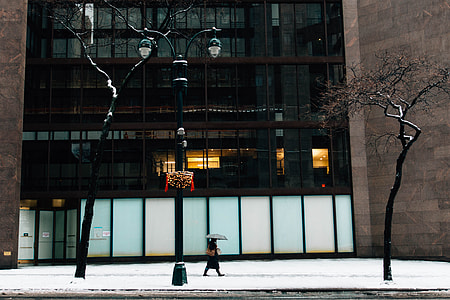 person walking near building while holding umbrella thumbnail