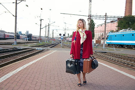 woman holding three assorted bags standing near train rails thumbnail